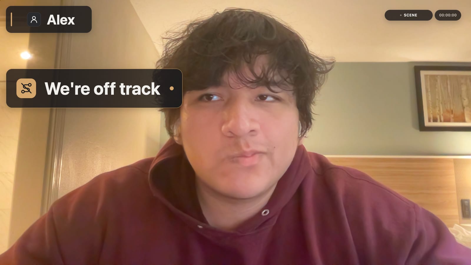 Alex on a video call with a Sceneuron sign on his video that reads “We're off track”, next to his name label.